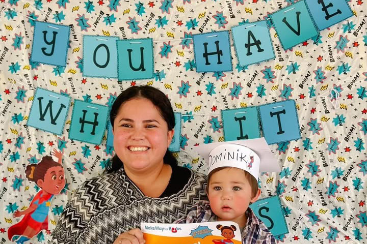 A teen girl holding a toddler boy in front of a banner reading You Have What It Takes