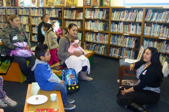 Children and their parents sit in the library listening to a book reading
