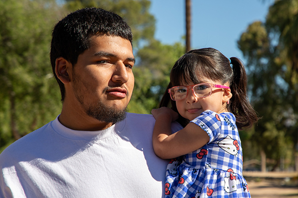 A teen boy holds his toddler daughter