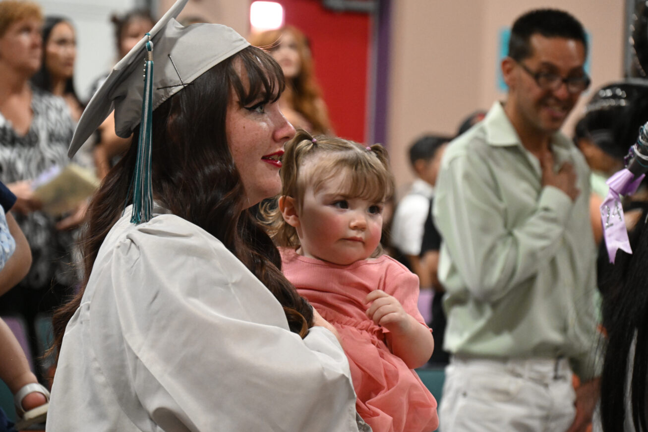 A TAP student in her cap and gown holds her daughter